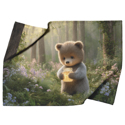 Baby_Bear_Holding_Glowing_Honey_Jar_In_P_H_Blanket_Top_Bottom_Folds_Mockup.png